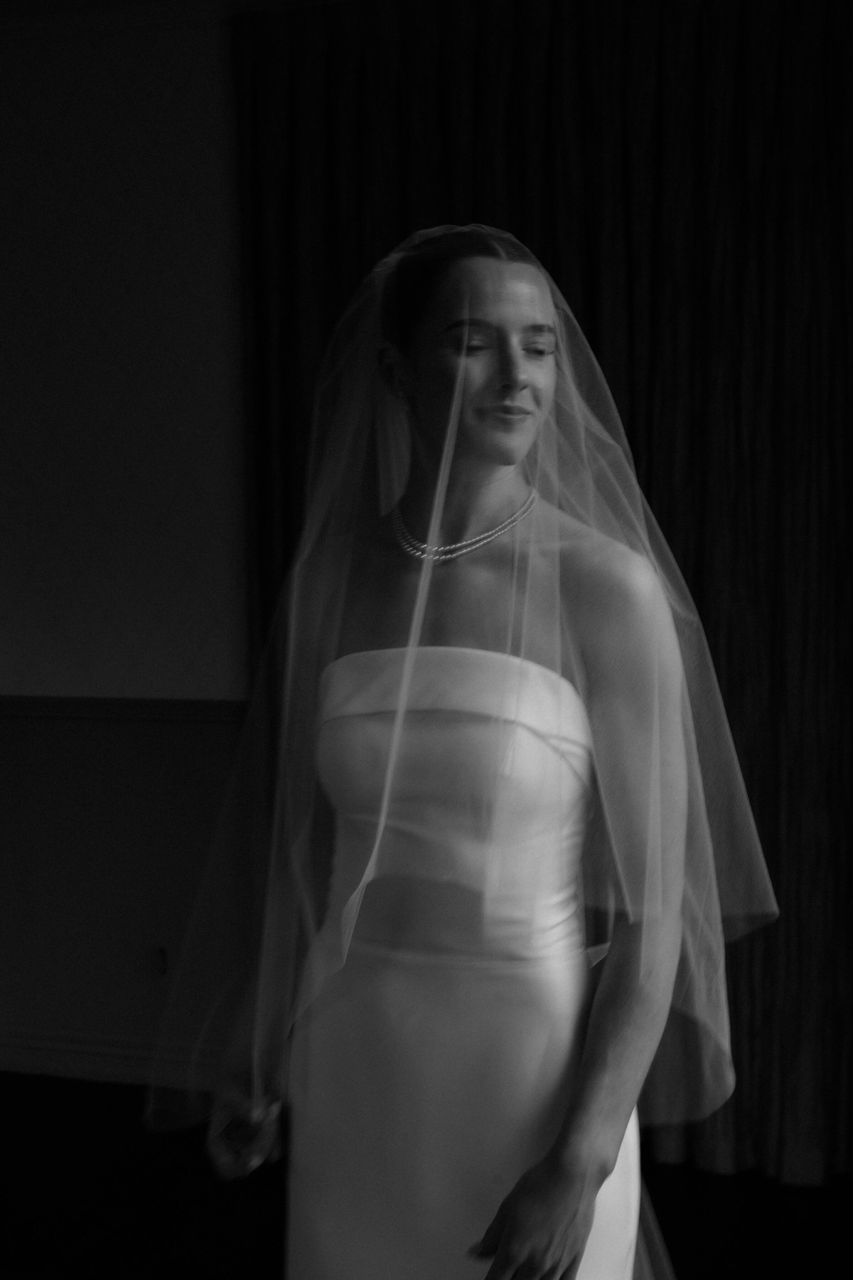 Bride under her veil in soft window light
