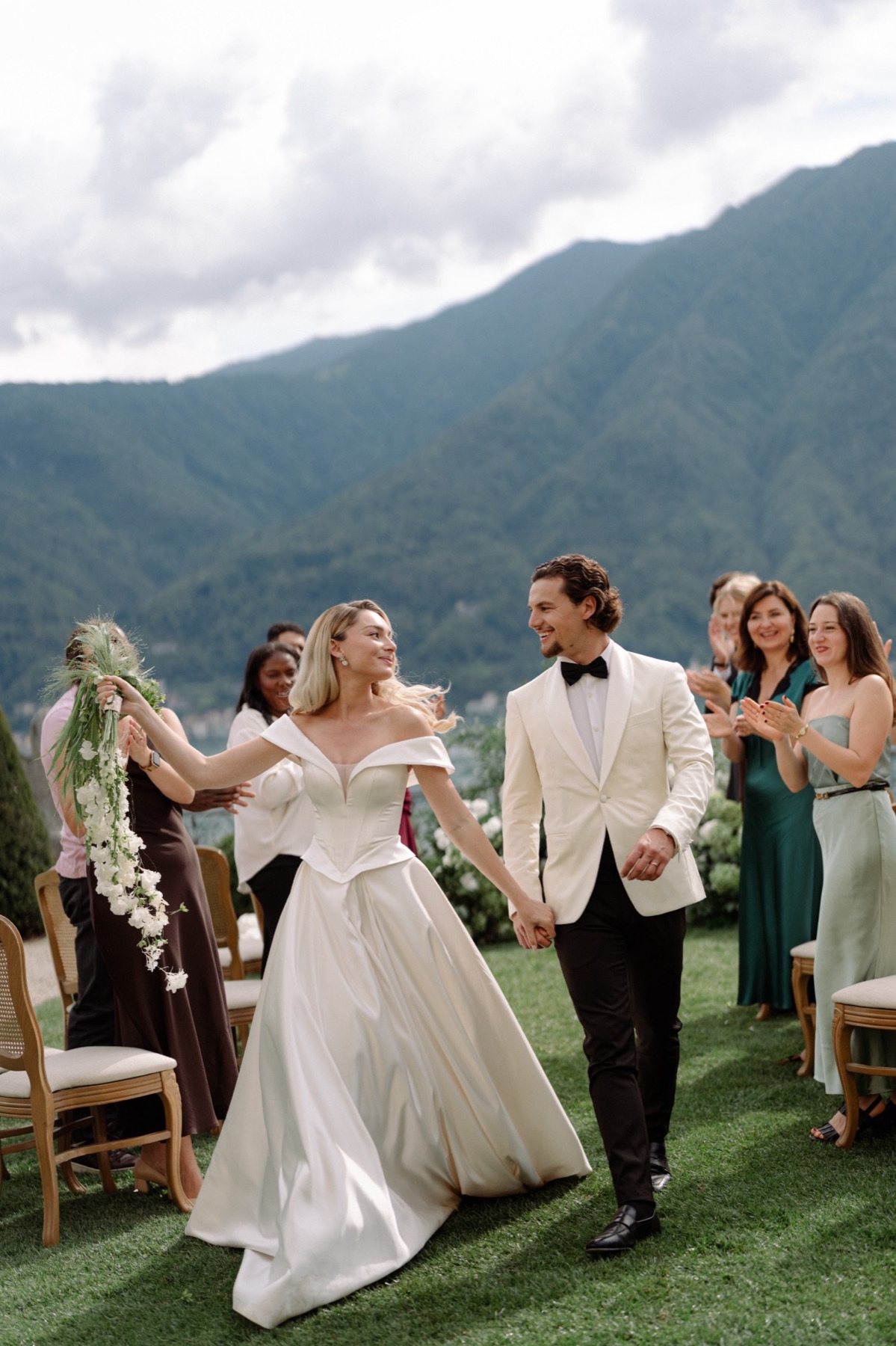 Couple walking back down the aisle at Lake Como as guests applaud