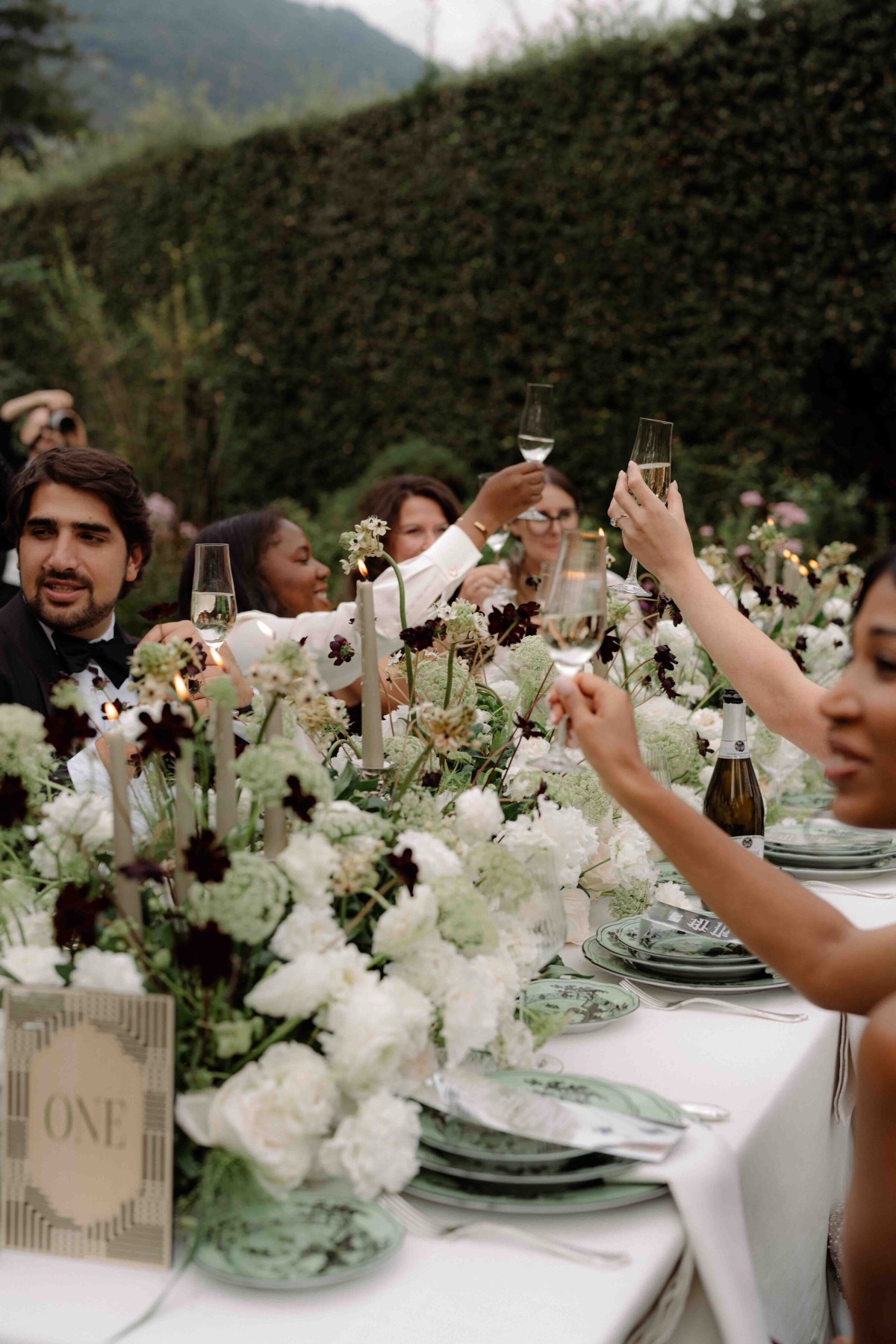 Guests raising a toast at a long floral table in Italy