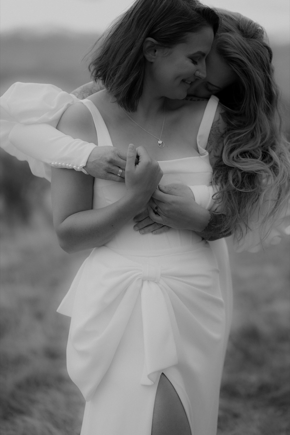 Two brides laughing in an embrace