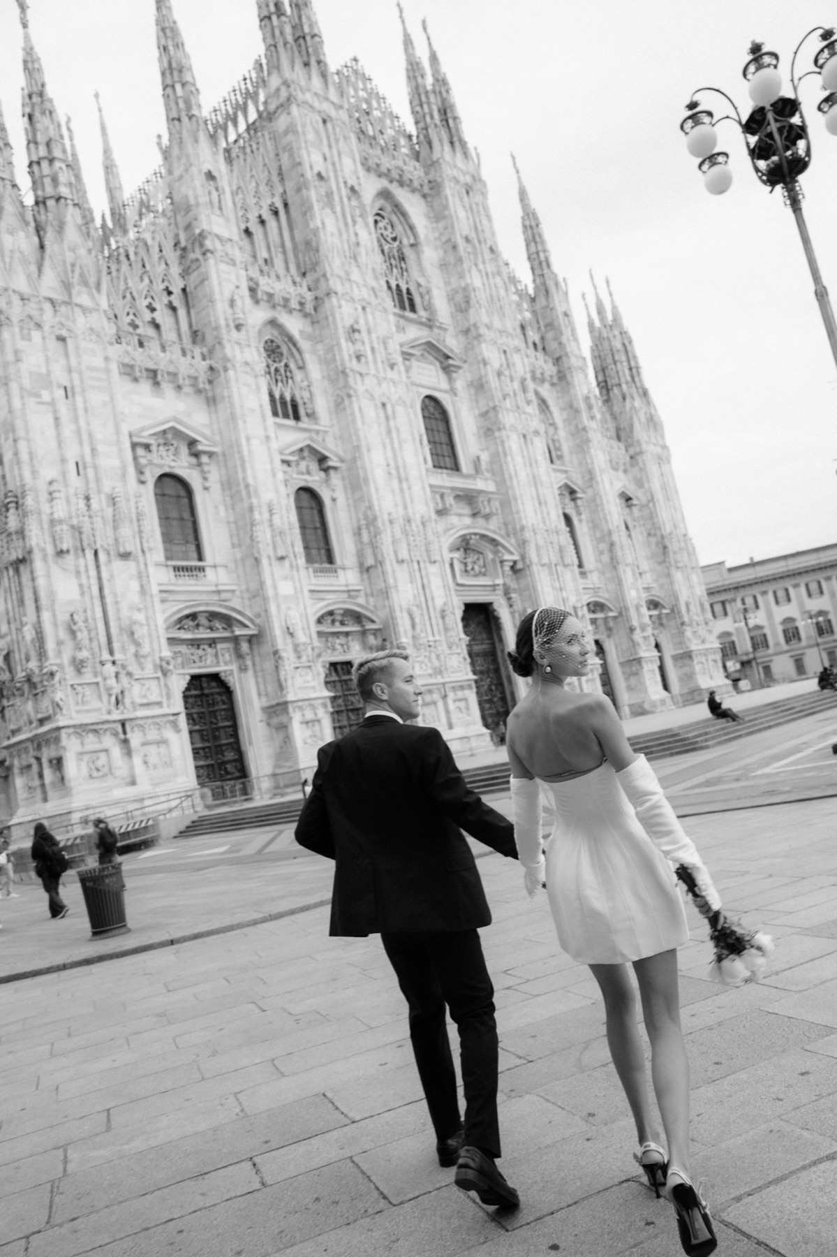 Couple walking hand in hand past the Milan Duomo