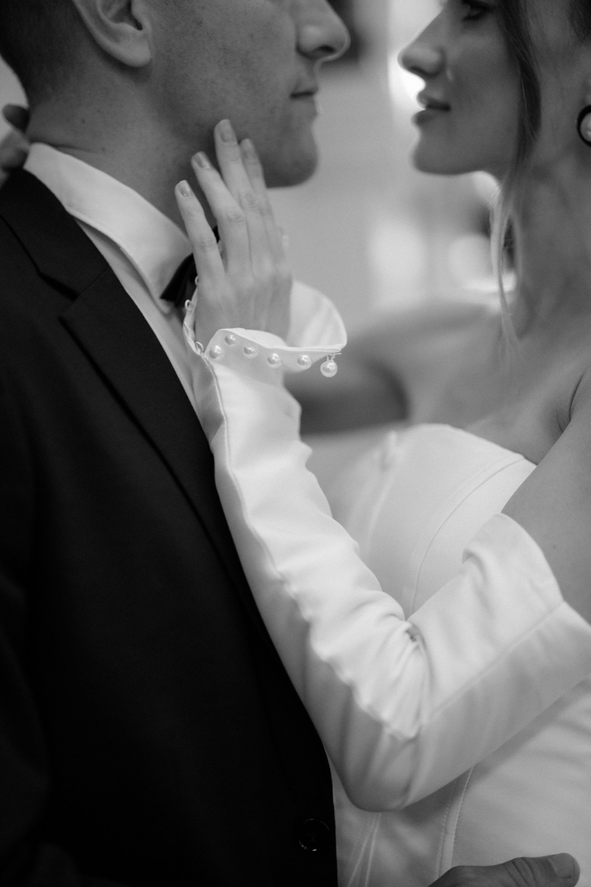 Bride's pearl-cuffed hand on her groom's cheek