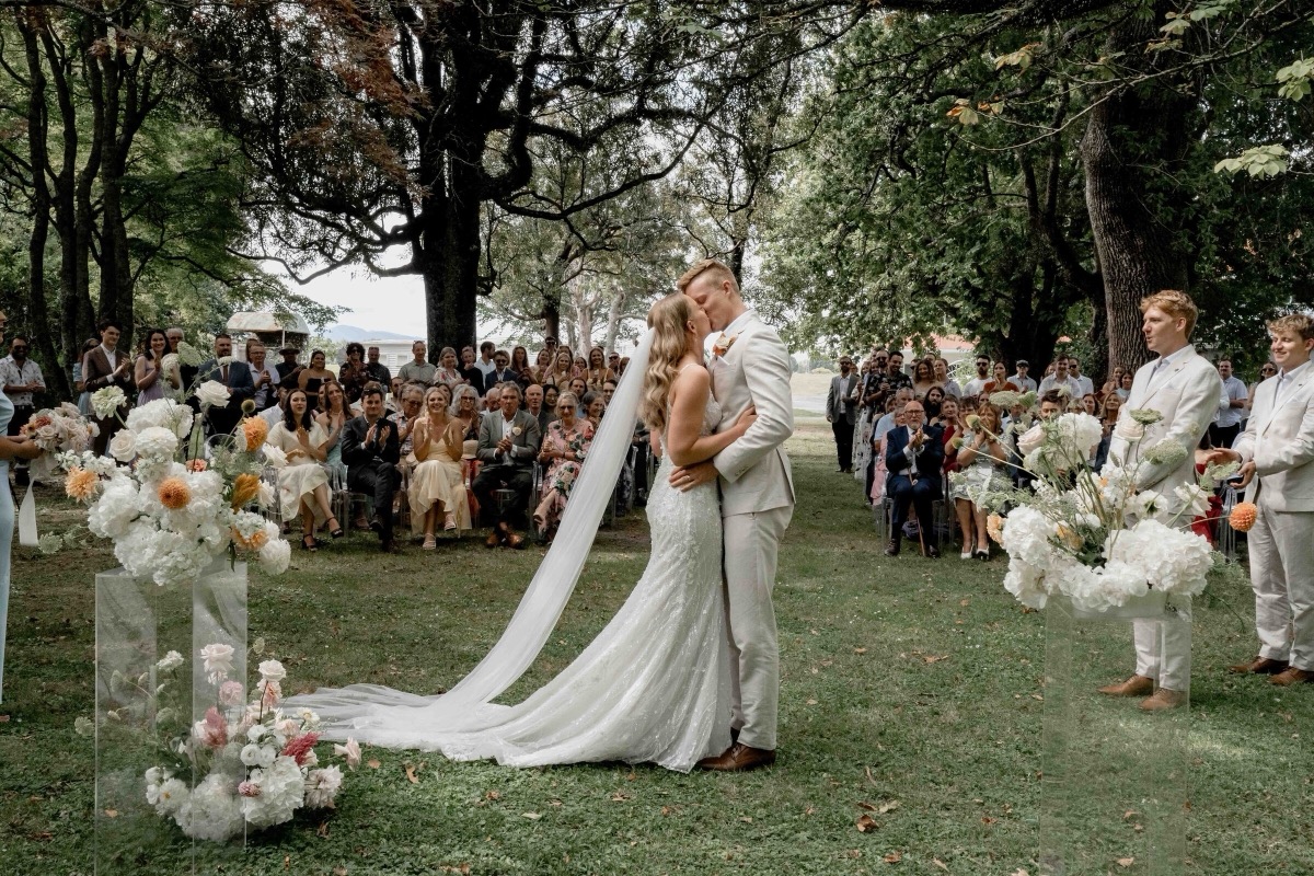 Couple kissing at a garden ceremony surrounded by guests