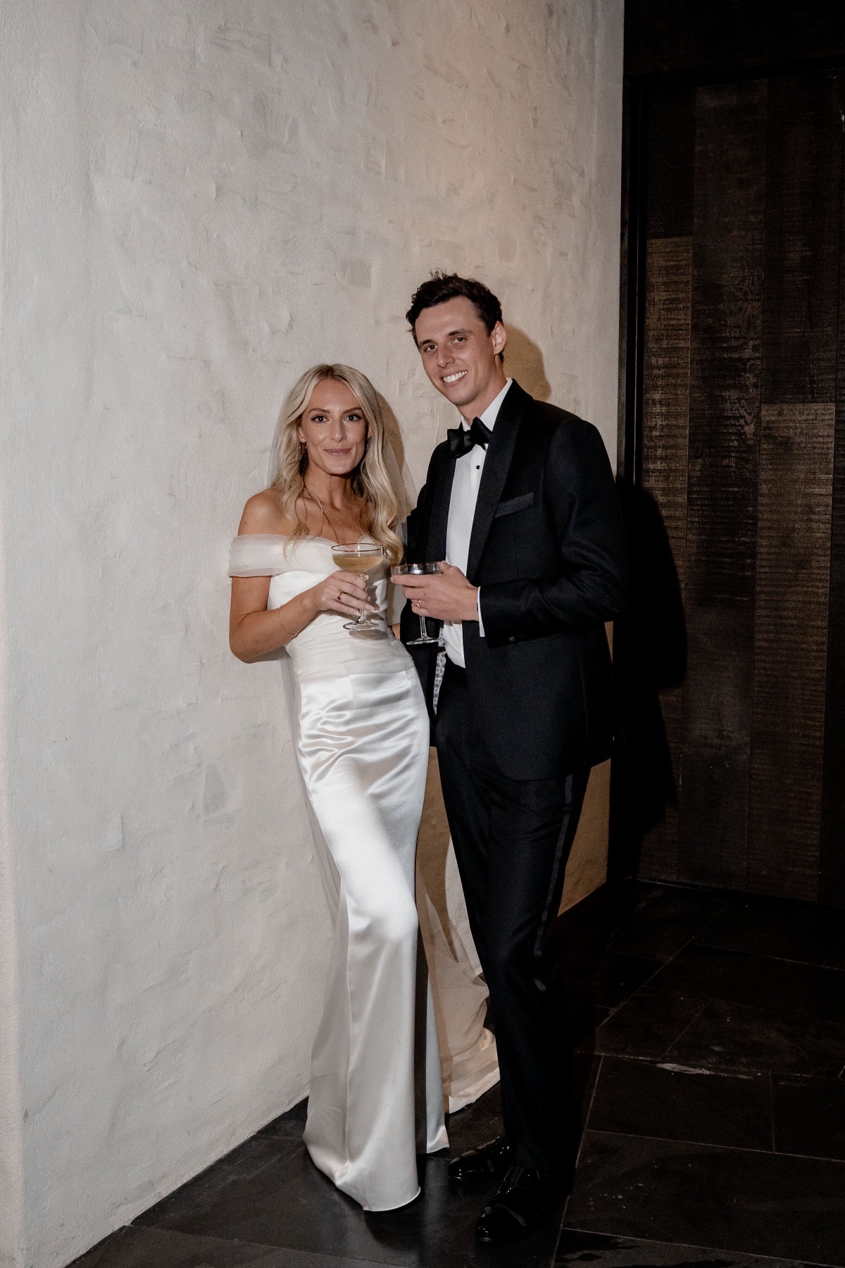 Couple sharing a drink against a white plaster wall